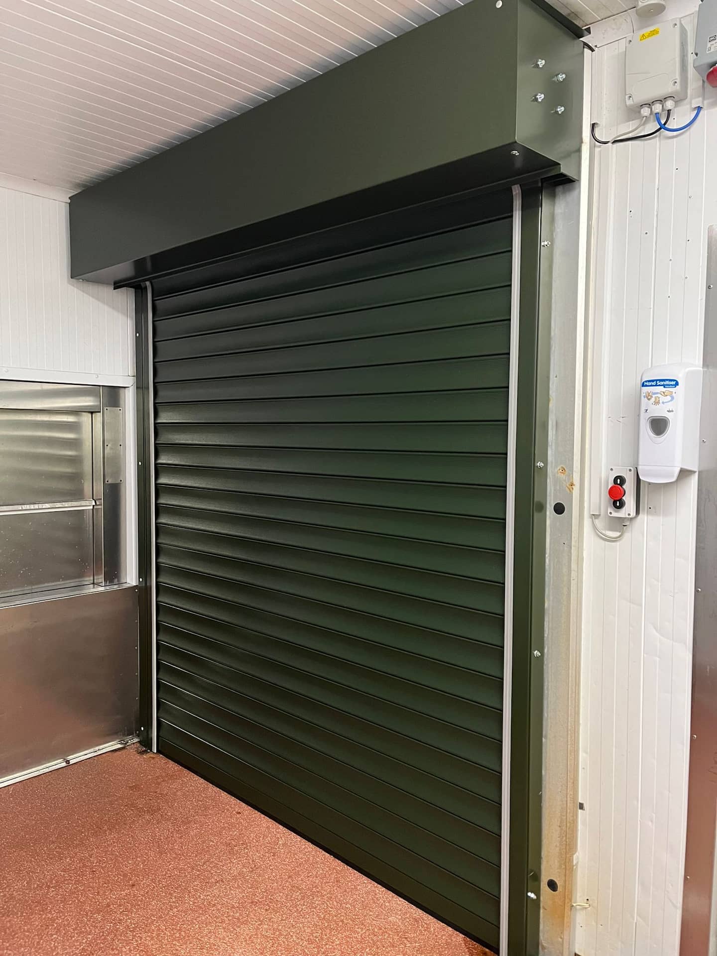 Juniper Green commercial steel roller shutter door fitted internally next to a stainless steel service area.