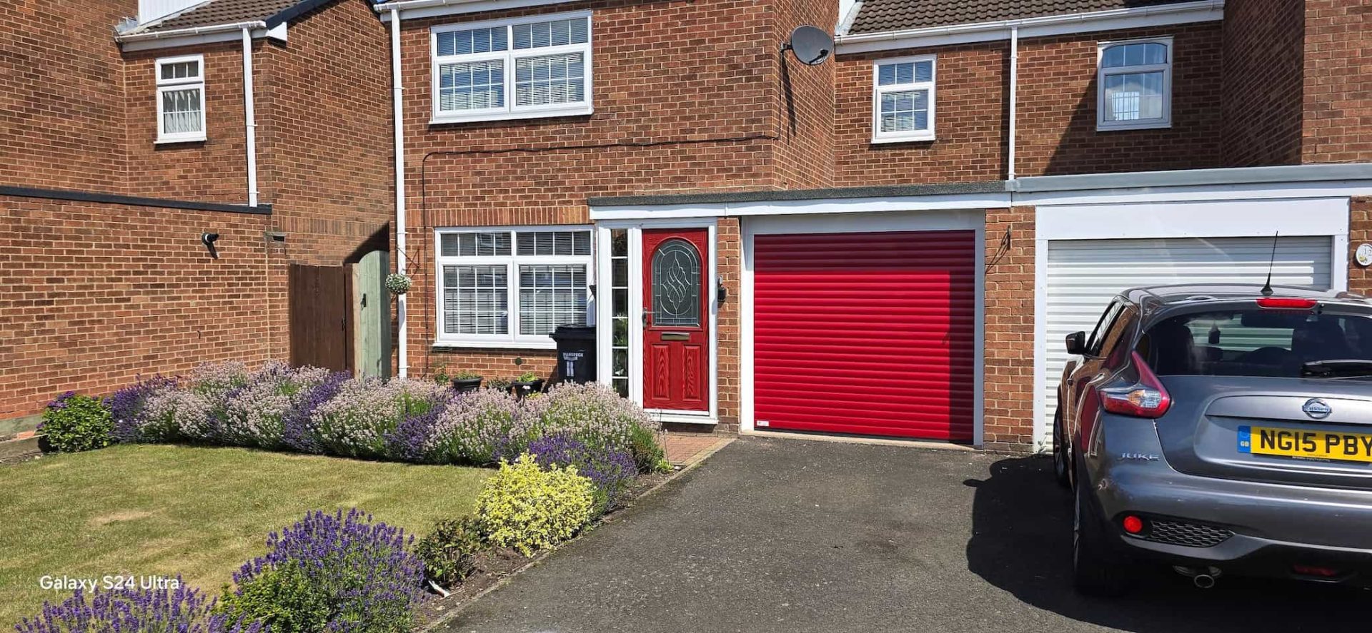 Burgundy red roller garage door fitted to a period stone house